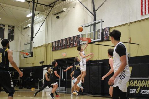 Jaden Goodall (11) attempts to get the ball into the hoop as number 14, Jojo Ballestero, struggles to defend. (Photo Provided by Michelle Andrei) 