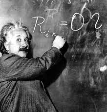 Albert Einstein is writing an equation on a chalkboard.